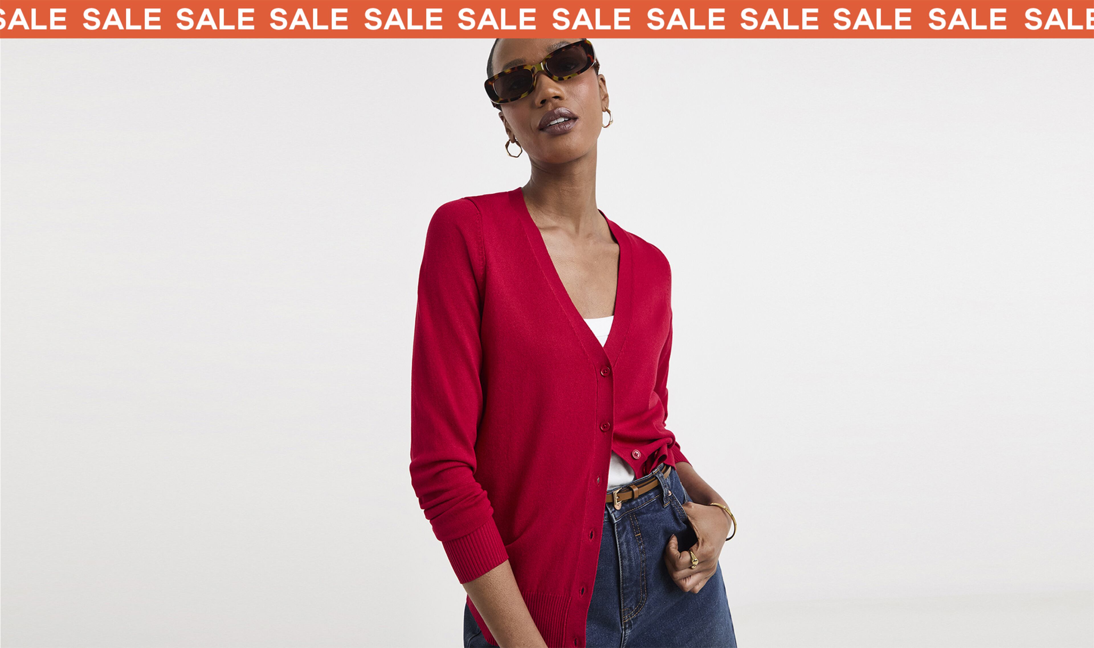 Woman wearing a red cardigan and jeans with a sale banner at the top
