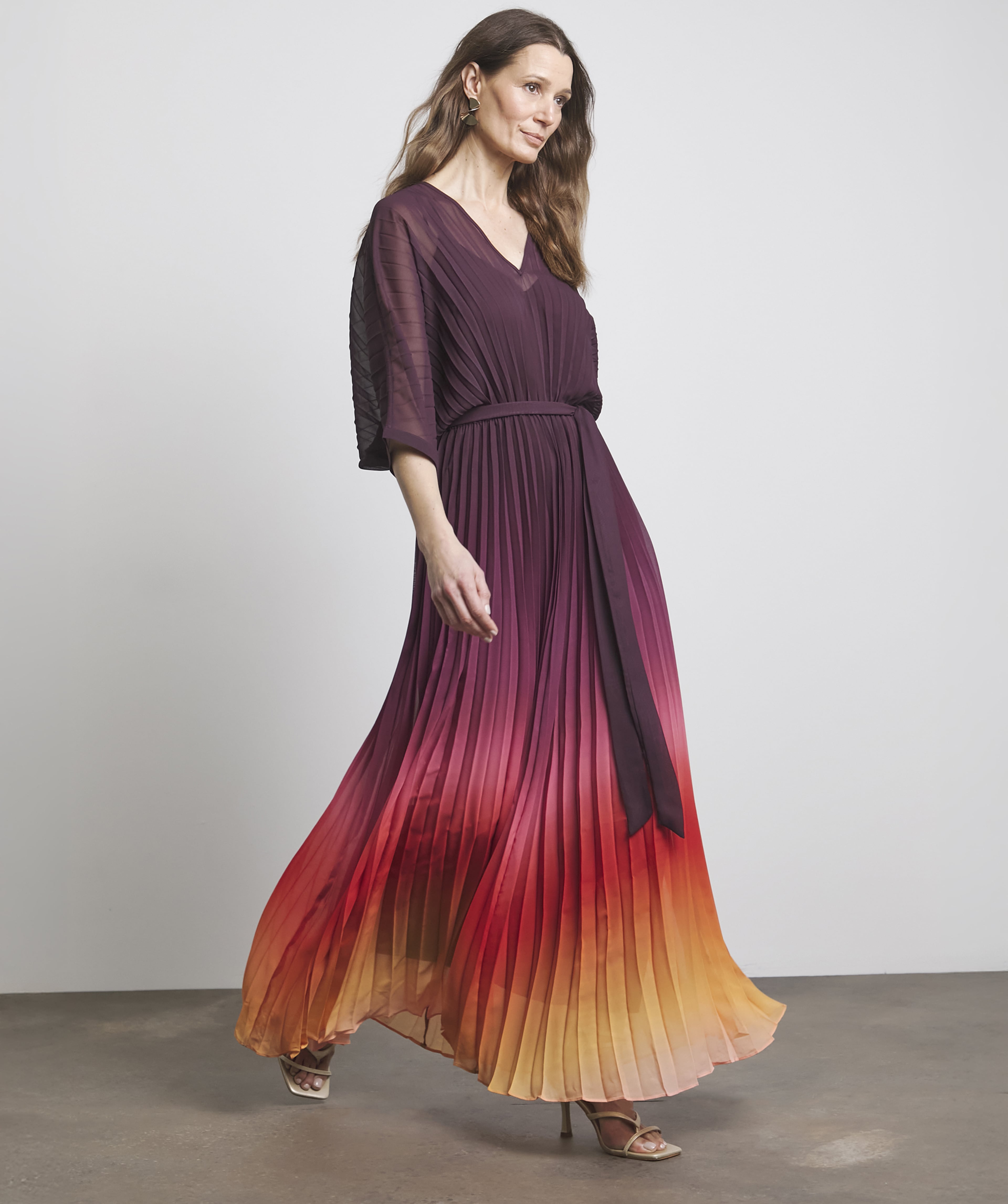 A woman stood wearing a burgundy and orange pleated summer dress